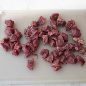 Cut up steak pieces on a cutting board.