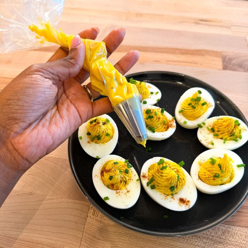 Piping bag with filling for deviled eggs with filled eggs.