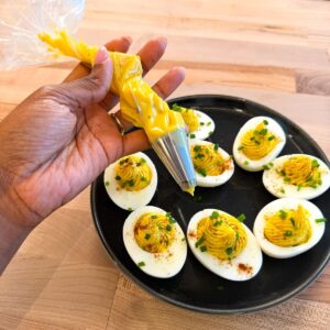 Piping bag with filling for deviled eggs with filled eggs.