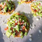 Ground beef tostadas topped with refried beans, lettuce, tomatoes, onions, queso fresco and cilantro lime sauce.