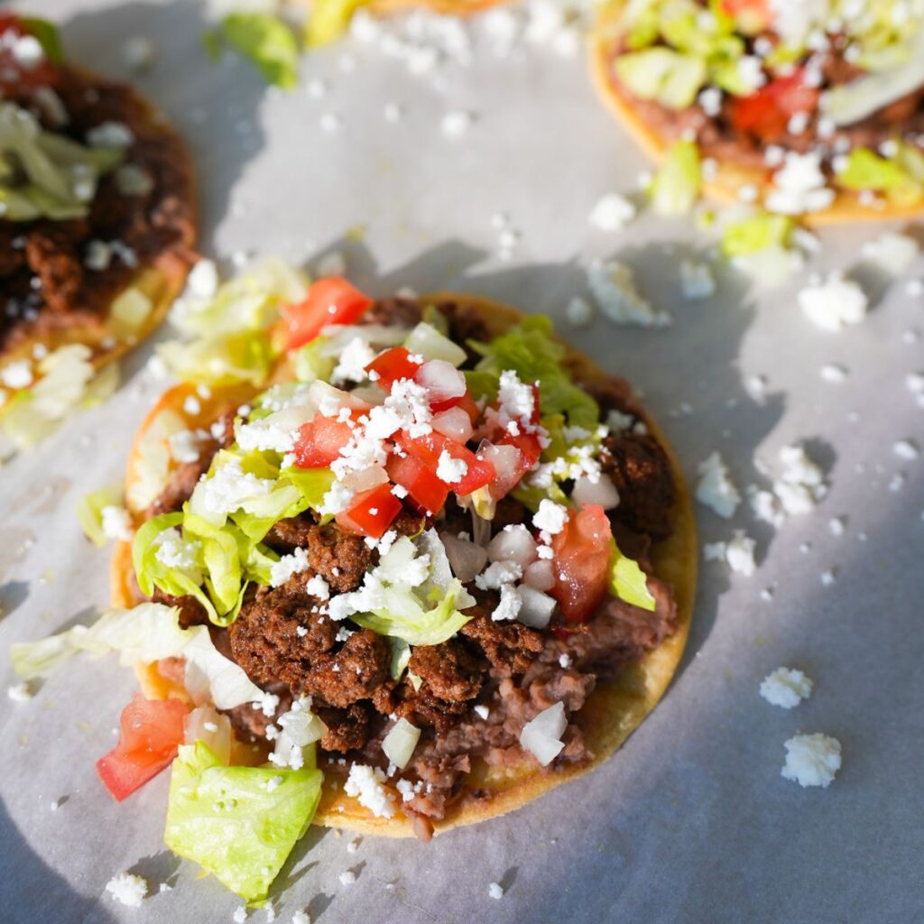 Ground beef tostadas topped with refried beans, lettuce, tomatoes, onions and queso fresco.