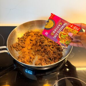 Ground beef in a skillet being seasoned with taco seasoning.