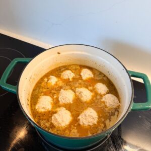 Dumplings in chicken broth before cooking.