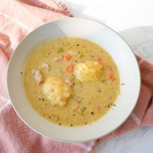 Chicken and dumplings in a bowl with tender chicken, carrots, celery, fluffy dumplings, and creamy broth.