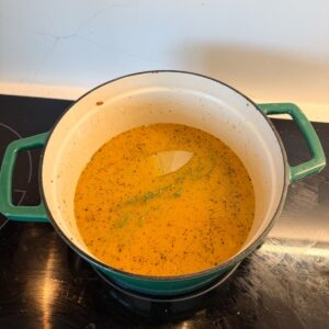 Broth for chicken and dumplings in a pot on the stove.