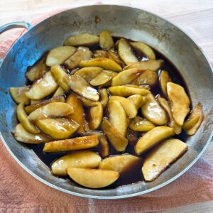 Southern fried apples in a skillet, coated in a glossy cinnamon sugar butter sauce.