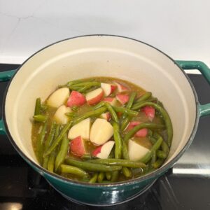 Green beans and potatoes in a pot with broth.