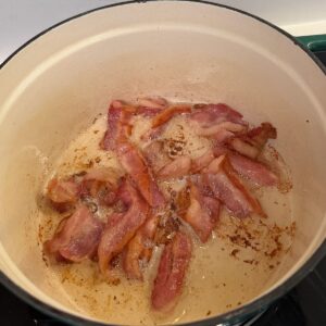 Bacon cooking in a dutch oven.