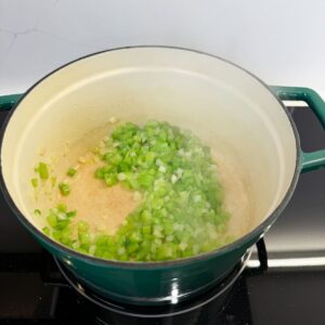 Bell peppers, onions and celery cooking in a dutch oven.