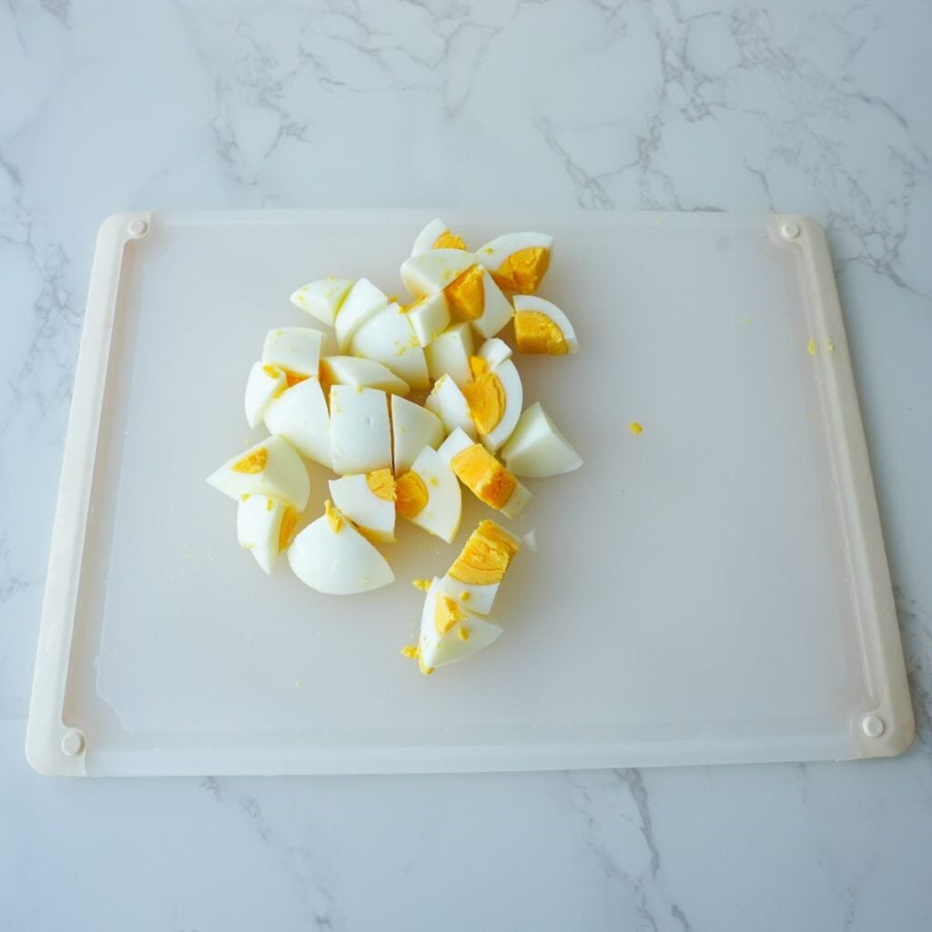 Eggs chopped up on a cutting board.