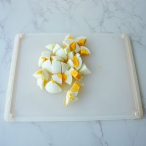 Eggs chopped up on a cutting board.