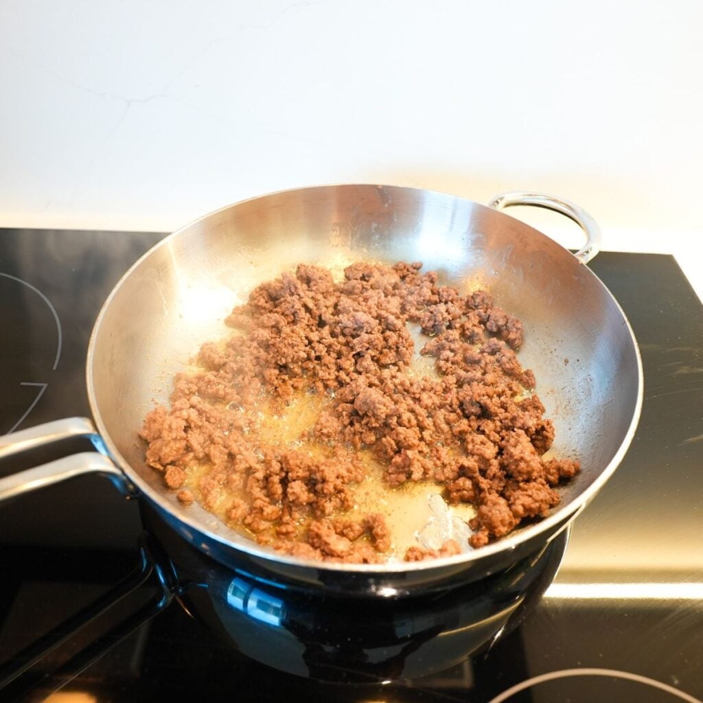 Ground beef browning in a skillet.