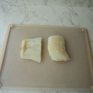 Cod fish filets on a cutting board.