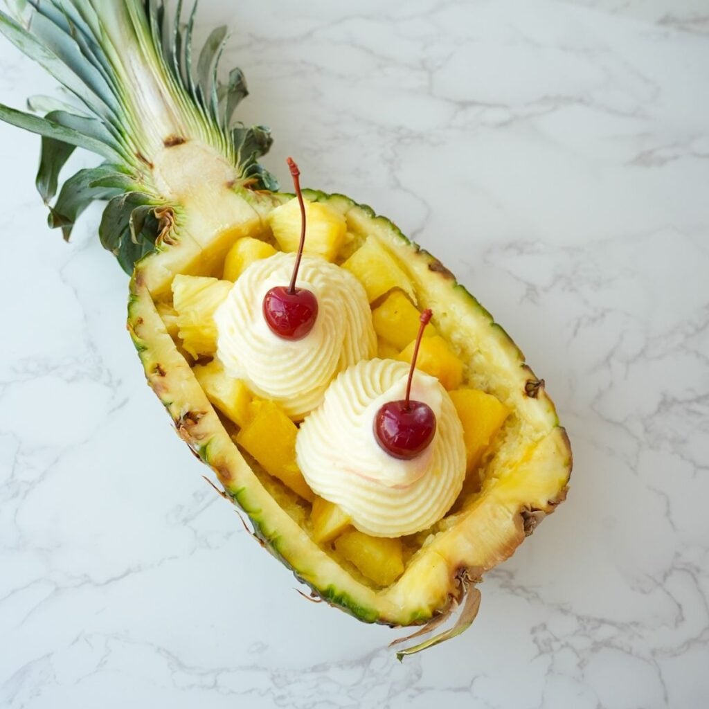 Copycat Dole Whip swirled inside a pineapple boat with a creamy soft serve texture.