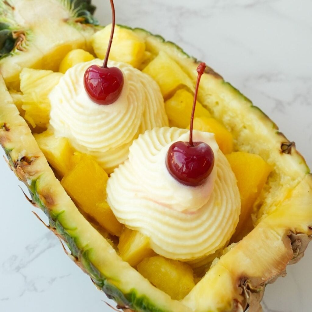 Copycat Dole Whip swirled inside a pineapple boat with a creamy soft serve texture.
