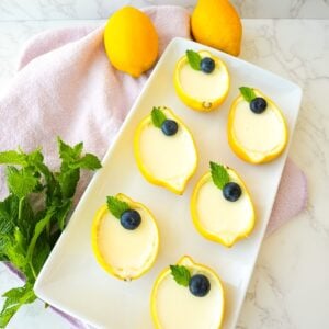 Lemon posset served inside hollowed lemon cups with blueberries on top.