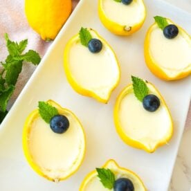 Lemon posset served inside hollowed lemon cups with blueberries on top.