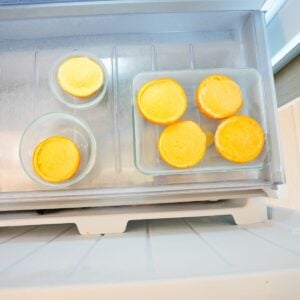 Frozen orange creamsicle cups served inside hollowed orange peels with a creamy orange filling in a freezer.
