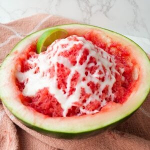 Shaved watermelon ice served in a watermelon half with lime juice and sweetened condensed milk drizzled on top.