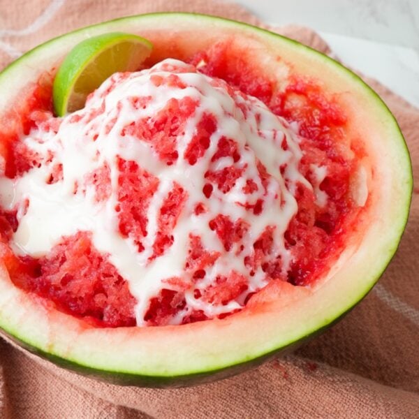 Shaved watermelon ice served in a watermelon half with lime juice and sweetened condensed milk drizzled on top.