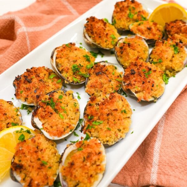 Baked littleneck clams topped with golden panko breadcrumbs, parsley, and lemon wedges on the side.