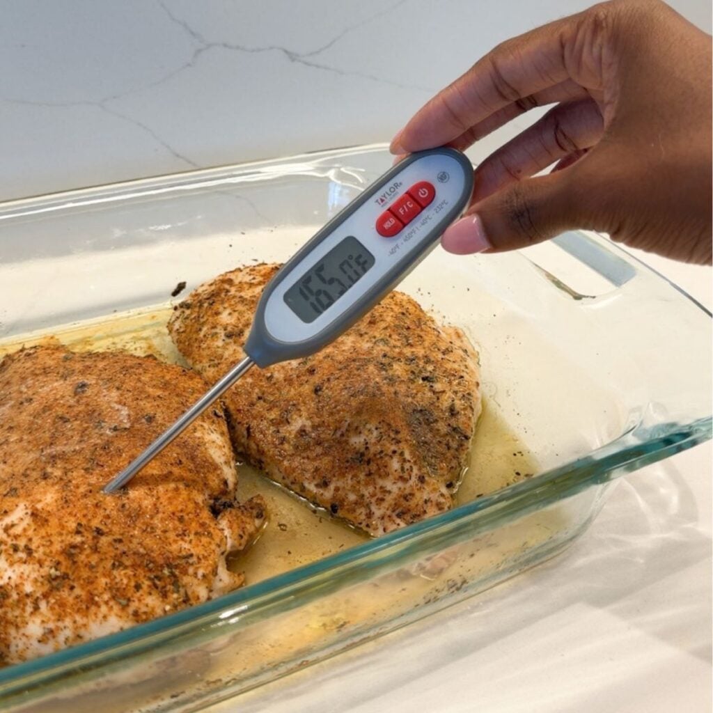 Thermometer taking temperature of chicken breast.