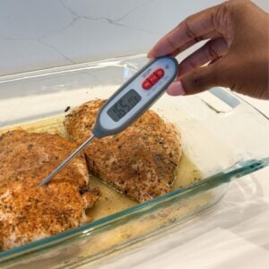Thermometer taking temperature of chicken breast.
