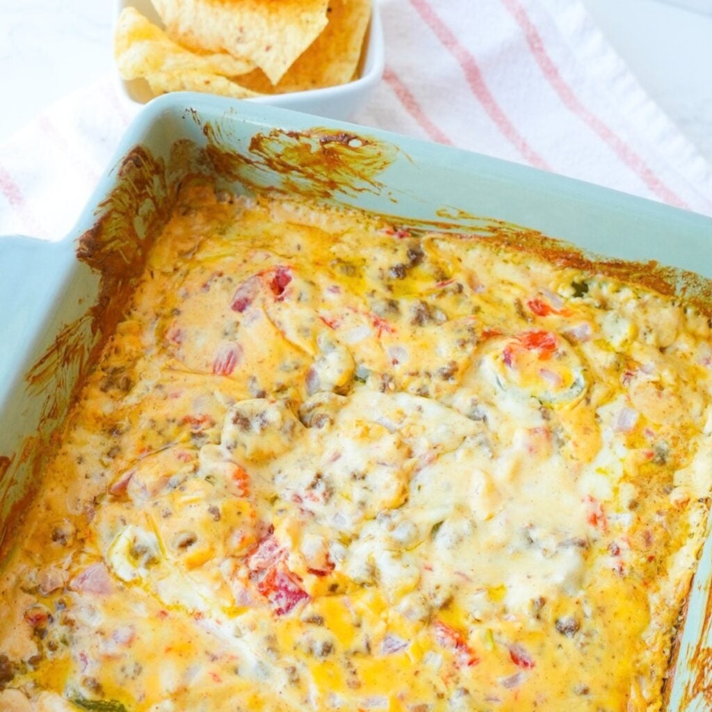 Baked Rotel dip with seasoned ground beef, melted cheese, tomatoes, onions, jalapeños, and tortilla chips.