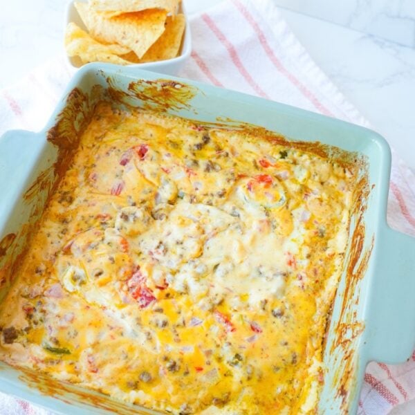 Baked Rotel dip with seasoned ground beef, melted cheese, tomatoes, onions, jalapeños, and tortilla chips.