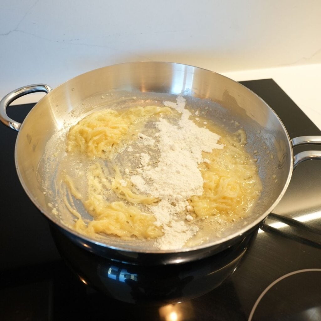 Flour added to cooked onions in a pan.