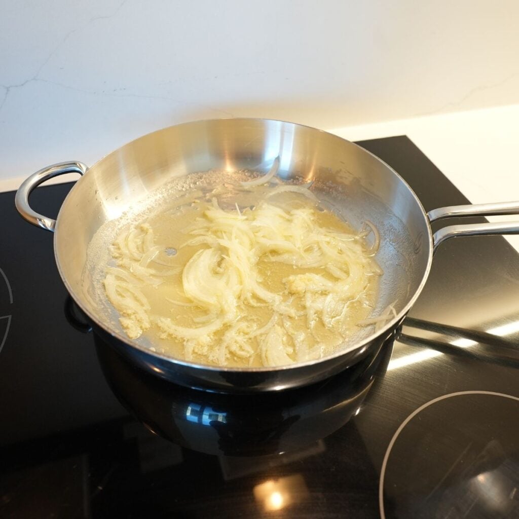 Onions cooking in butter in a pan.