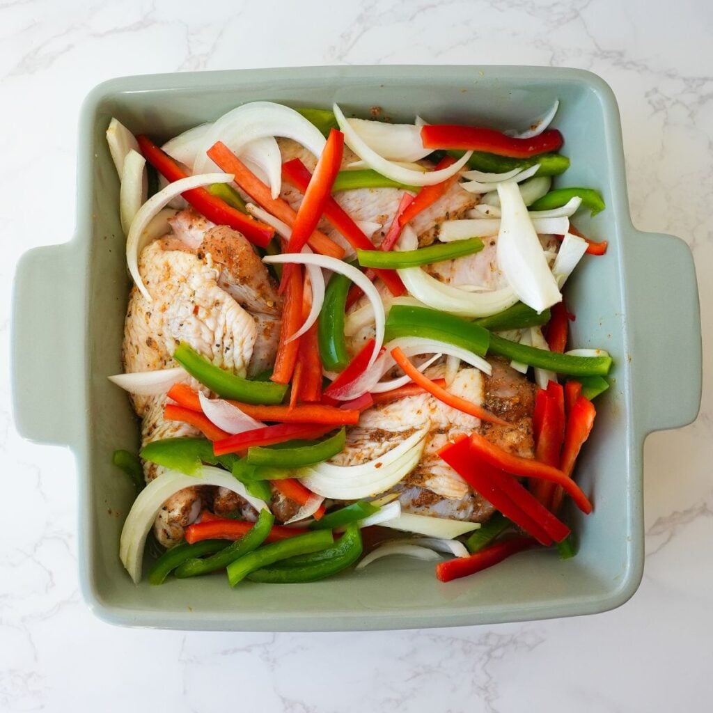 Turkey wings in a baking dish with onions and peppers before baking.