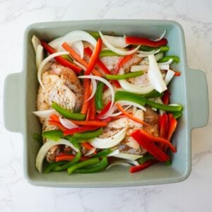 Turkey wings in a baking dish with onions and peppers before baking.